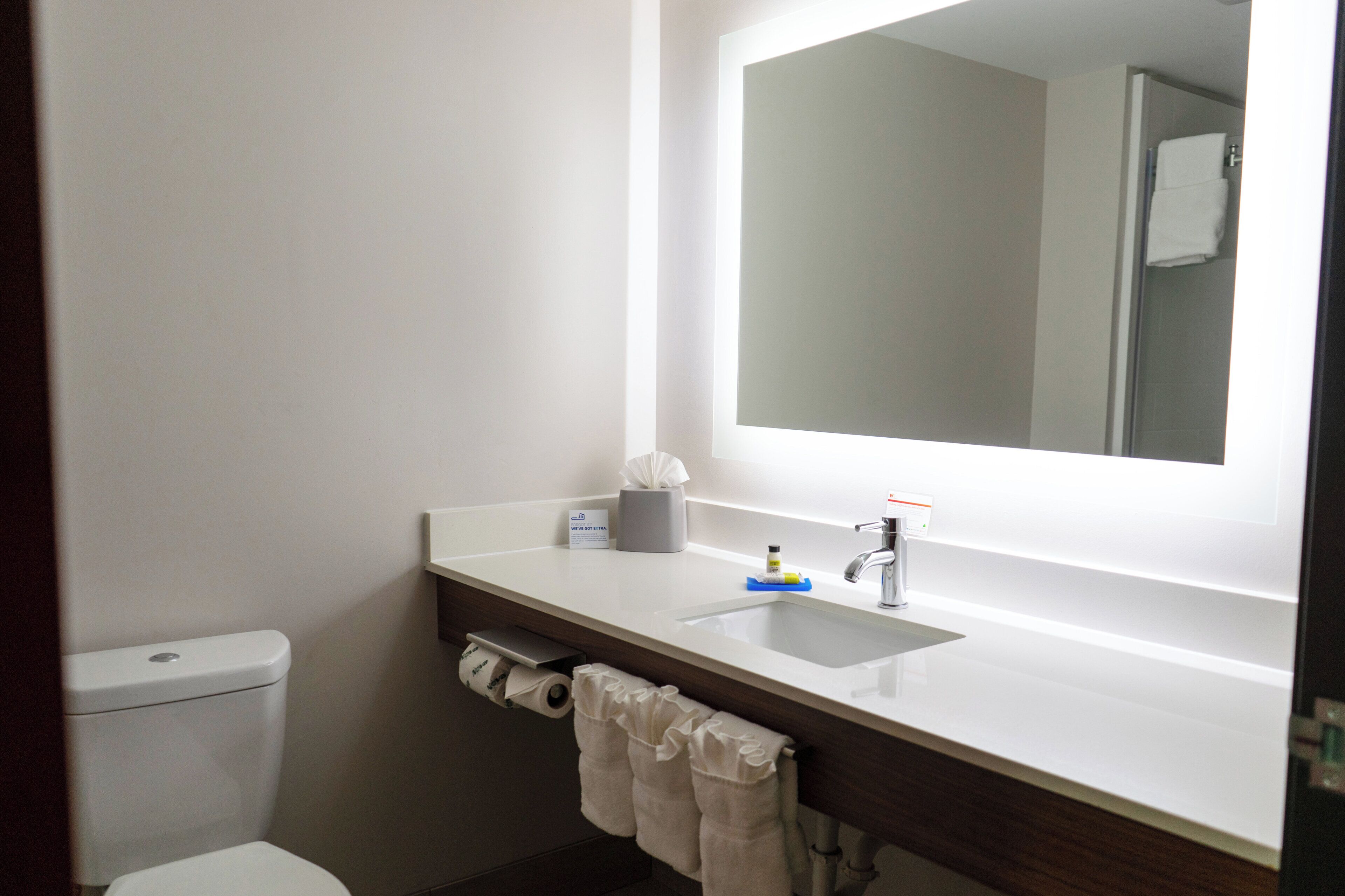 A bathroom with a white sink, a mirror, a towel rack, and a toilet.