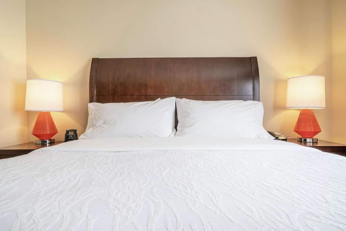 A hotel room with a large bed, two bedside lamps, and a wooden headboard.
