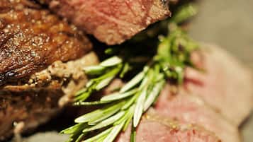 Une vue rapprochée d’un plat de viande cuit, dont une tranche a été coupée, et qui est décoré de romarin.
