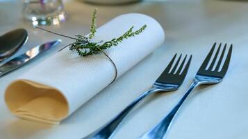 Une table joliment dressée, avec une serviette pliée, deux fourchettes et une cuillère.