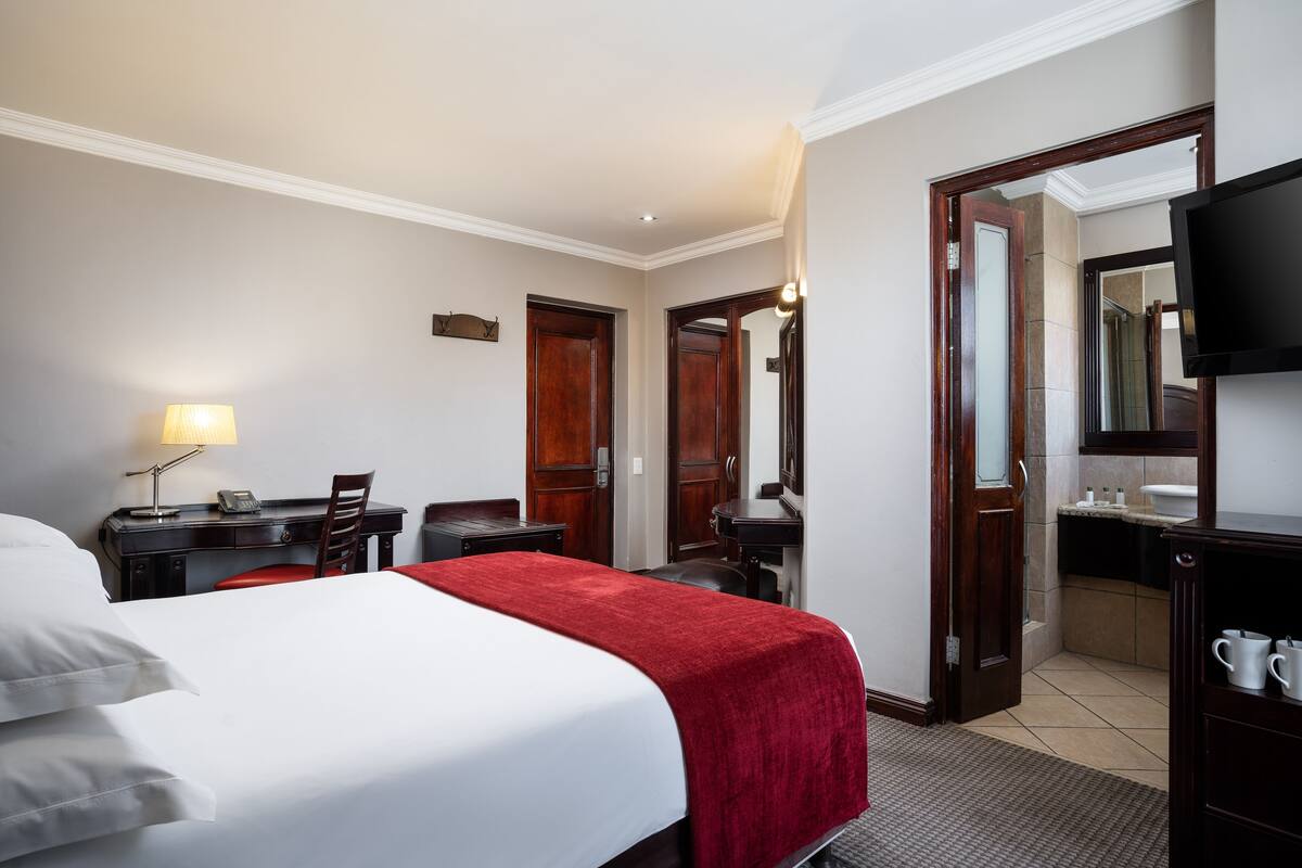 Una camera d'albergo con un letto, una scrivania, una sedia e una televisione.