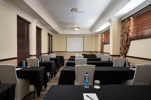 A conference room with multiple tables, chairs, and a projector screen.
