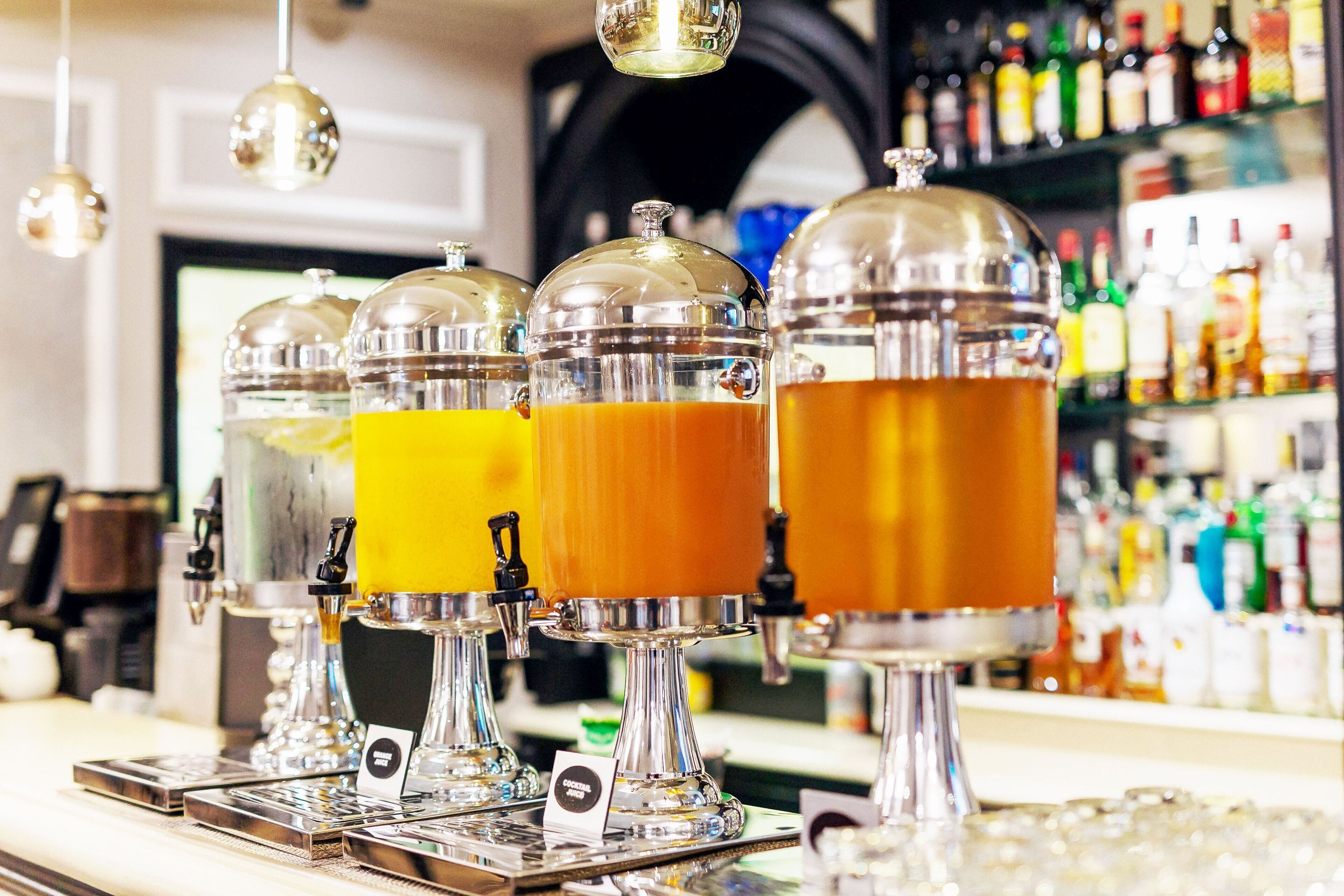 Un espace bar doté de plusieurs distributeurs de boissons, d’une sélection de bouteilles disposées en arrière-plan et d’un comptoir.