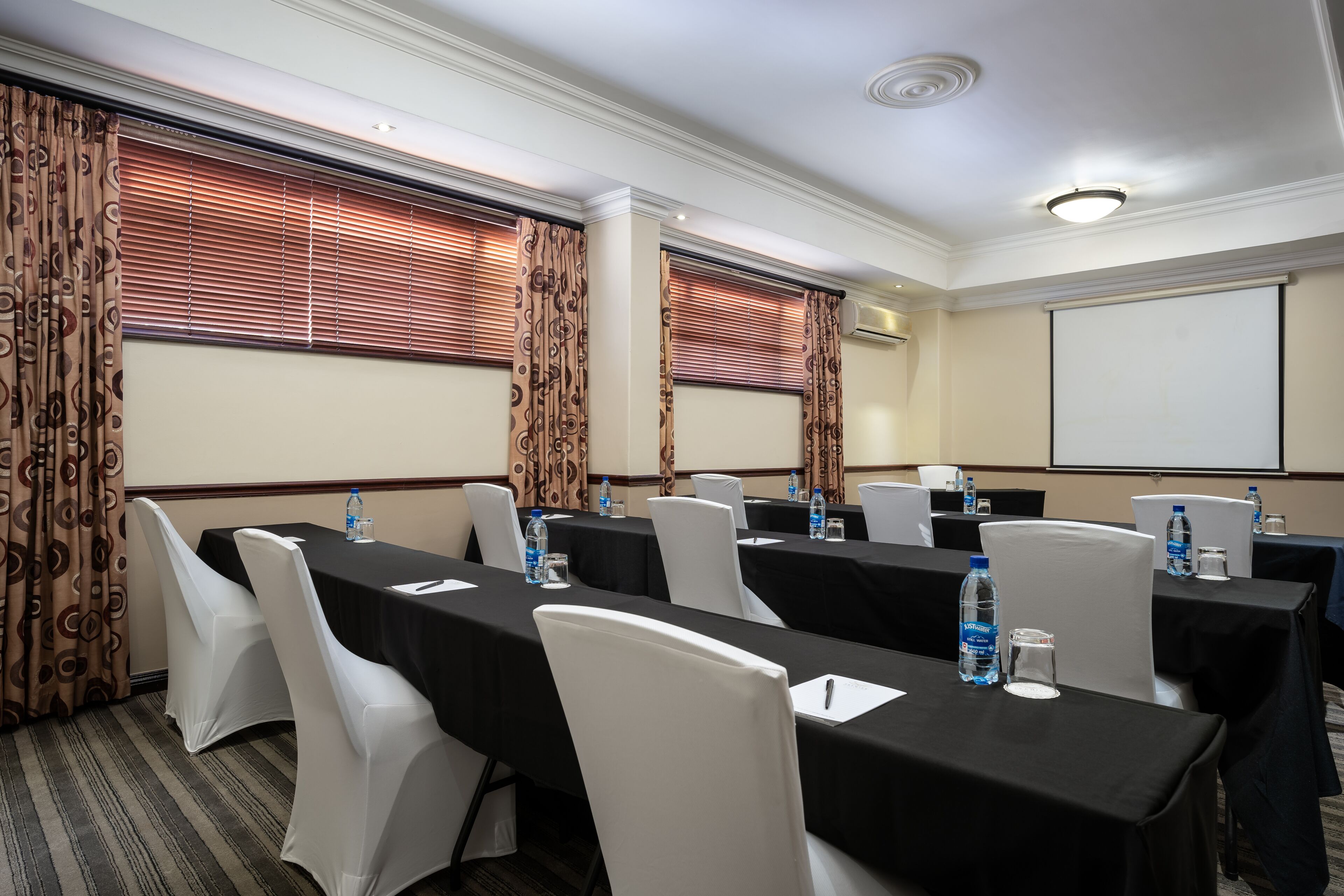 A conference room with tables, chairs, and a projector screen.