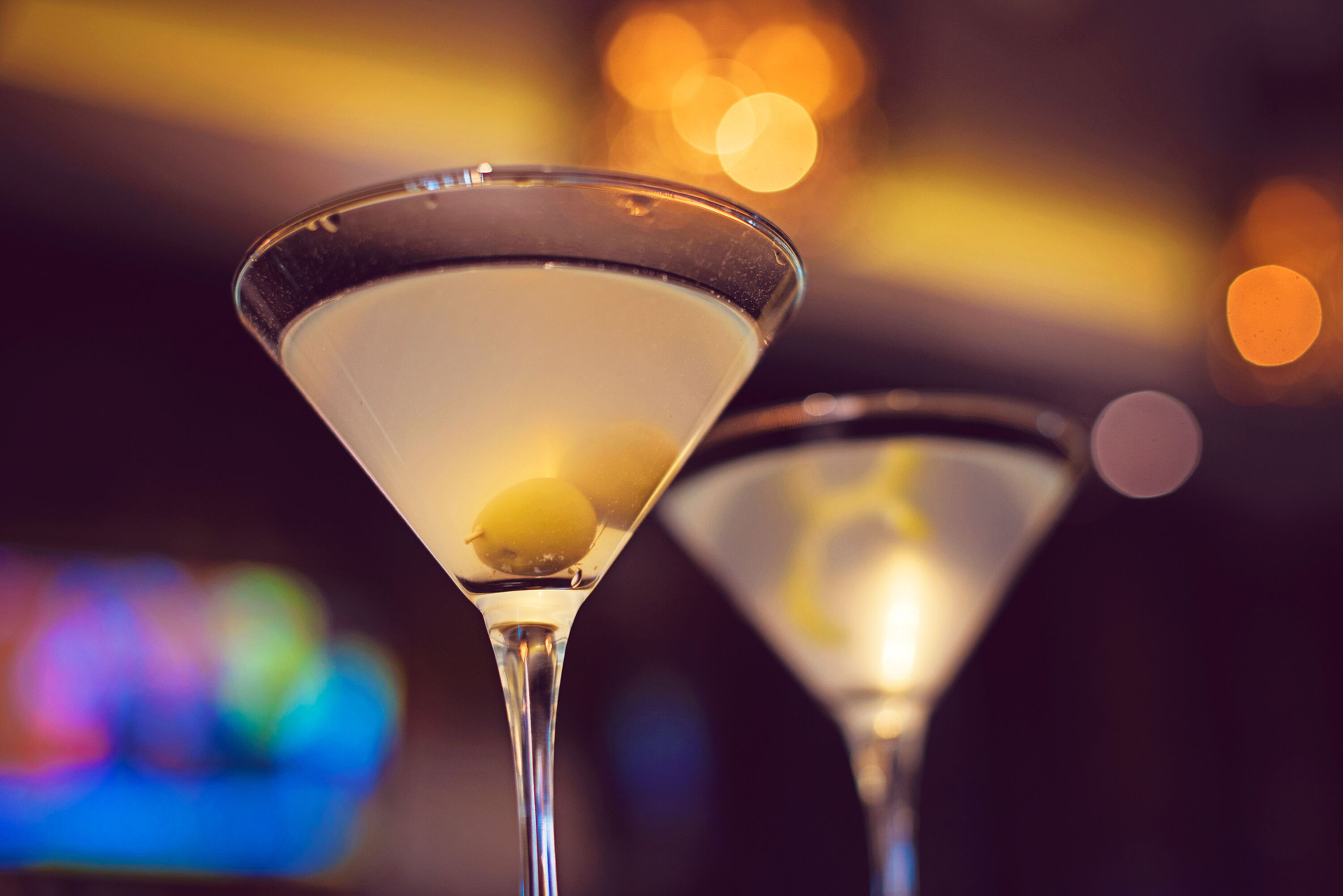 Twee martini glazen met een citroen twist op een bar.