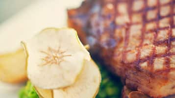 Un plato con un filete a la parrilla, una rodaja de manzana y guisantes verdes.