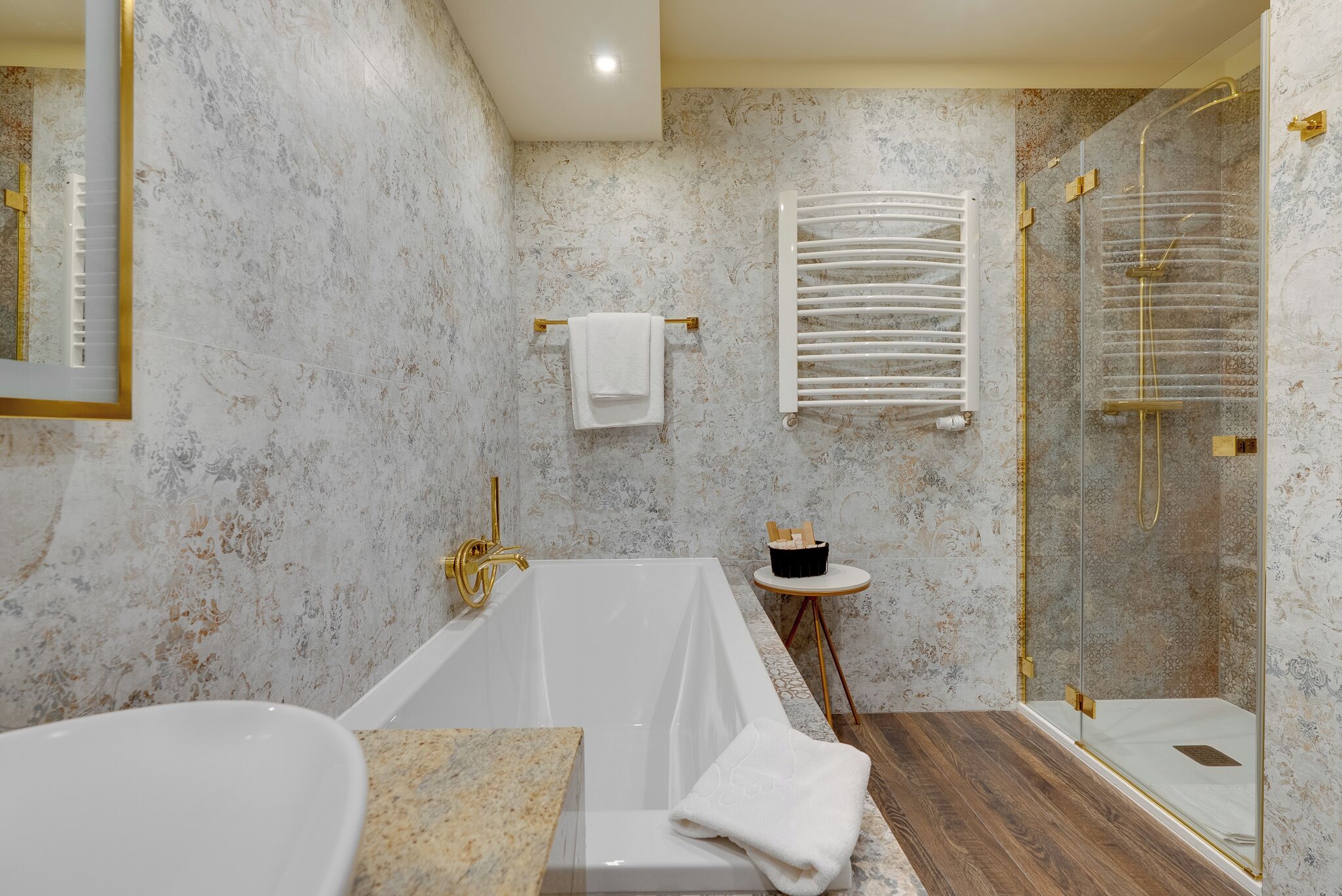 A bathroom with a bathtub, a glass-enclosed shower, a towel rack, and a small table with toiletries.