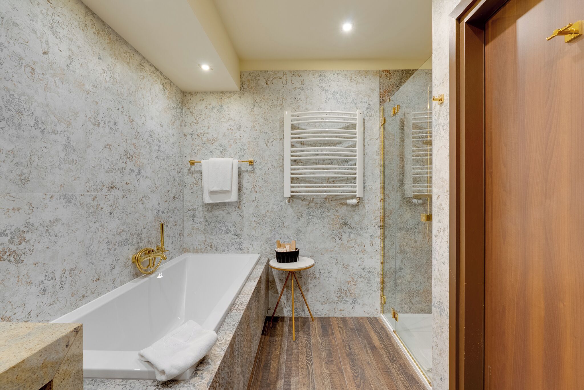 Un baño con bañera, ducha y una pequeña mesa redonda con una toalla.