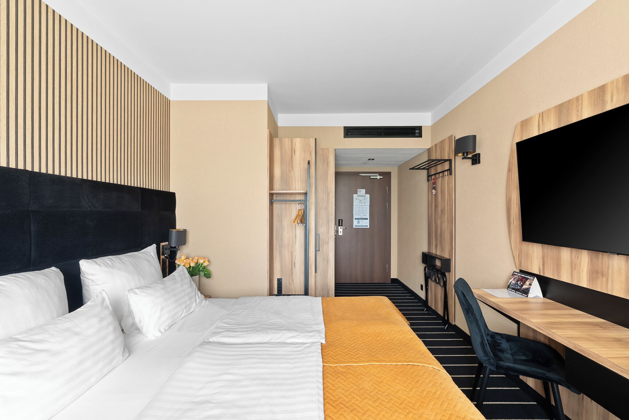 A hotel room with a bed, a desk, a chair, a TV, and a staircase leading to another room.