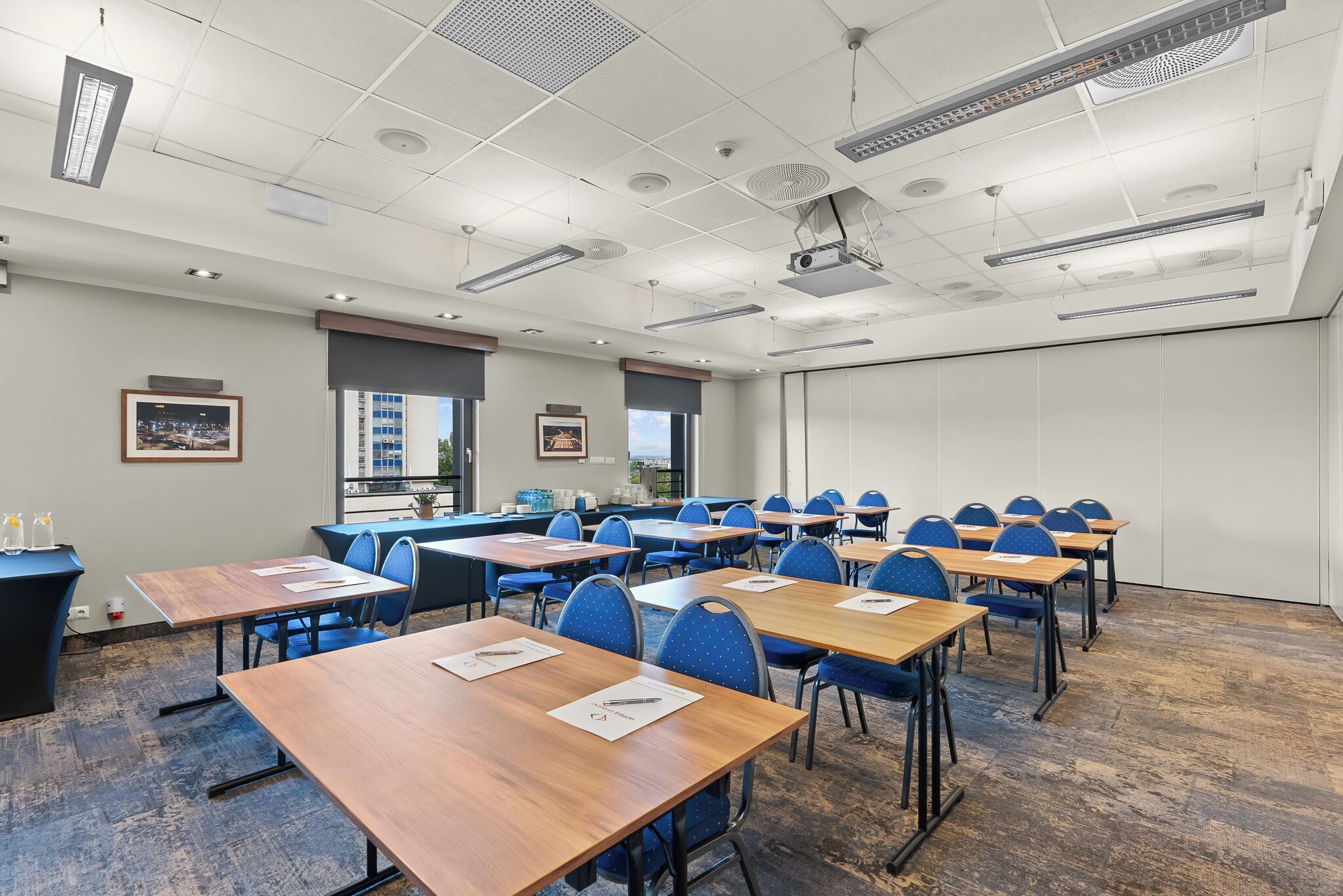 A conference room with tables, chairs, and a projector screen.