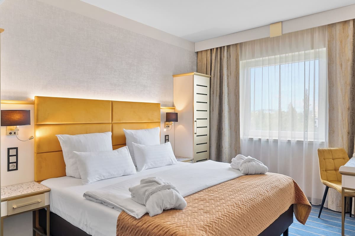 Een hotelkamer met een groot bed, een bureau, een stoel en een kledingkast.