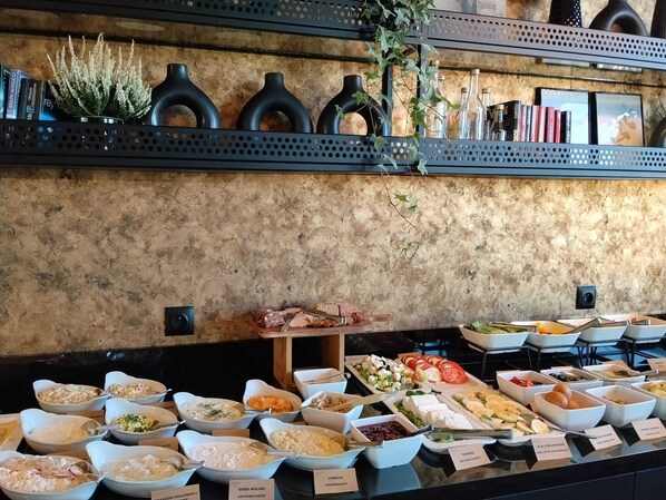Un bufé con diversas opciones de comida y una pared rústica adornada con jarrones y plantas.