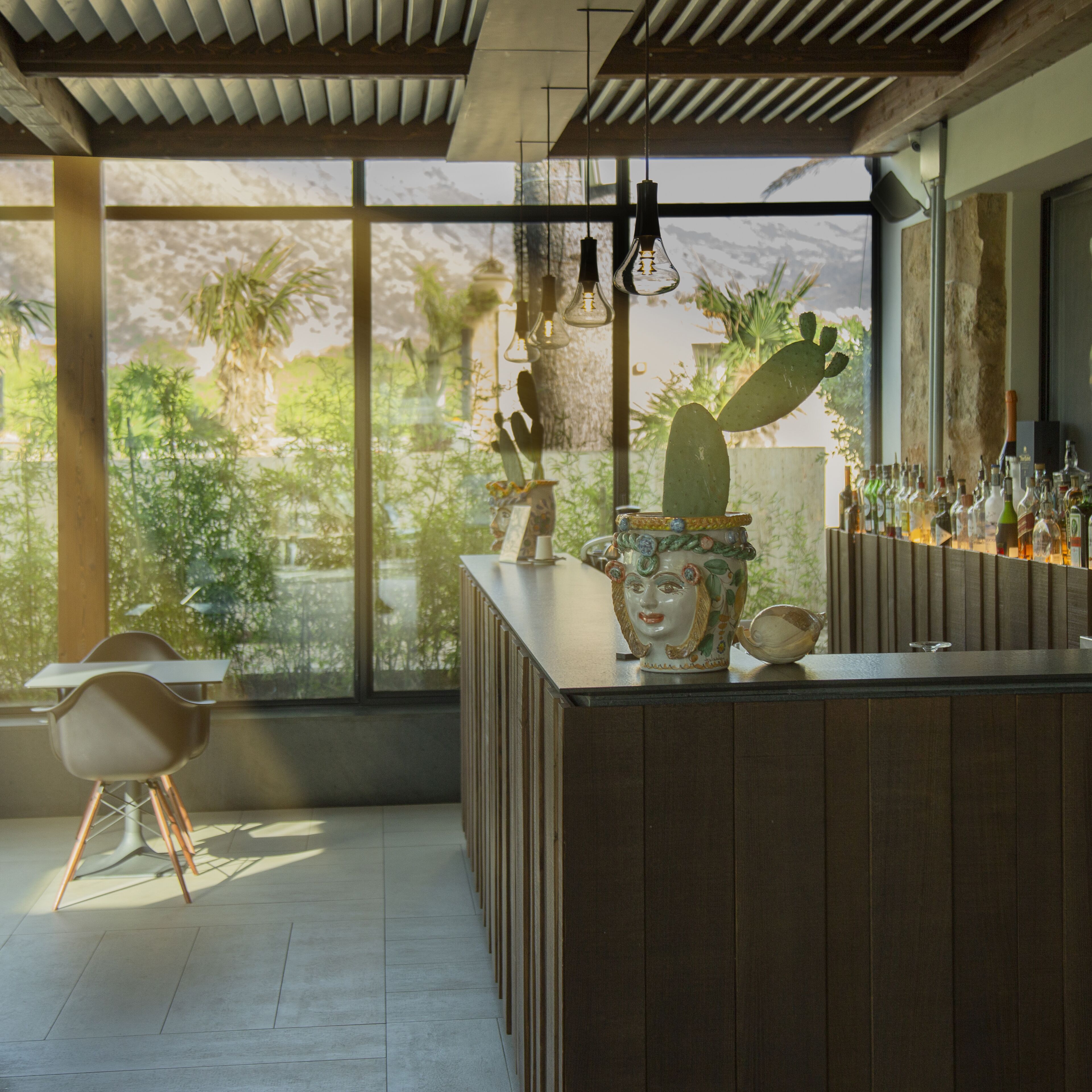 Un bar moderno con un ventanal grande, paneles de madera y una decoración con cactus.