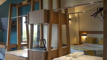 Ein Hotelzimmer mit einem Bettgestell aus Holz, einem eingebauten Schreibtisch mit Wasserkocher und einem großen Spiegel.