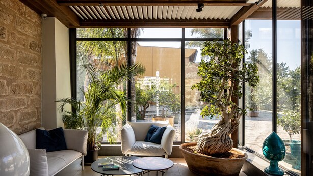 A modern interior with a white sofa, a round table, and a large window with a view of the outside. - Magaggiari Hotel Resort (Cinisi)
