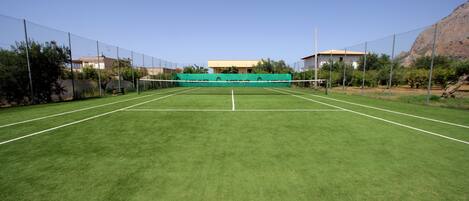 A tennis court with a net in the center, surrounded by a chain-link fence.