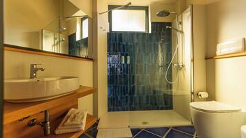 A bathroom with a glass-enclosed shower, a sink, and a toilet.
