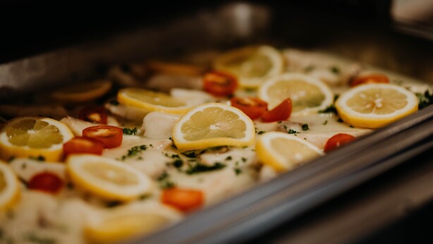 A dish with lemon slices, tomatoes, and herbs. - Sonnenhotel Hoher Hahn (Schwarzenberg/Erzgeb.)