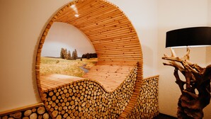 A circular wooden wall with a view of a grassy field and trees. - Sonnenhotel Hoher Hahn (Schwarzenberg/Erzgeb.)