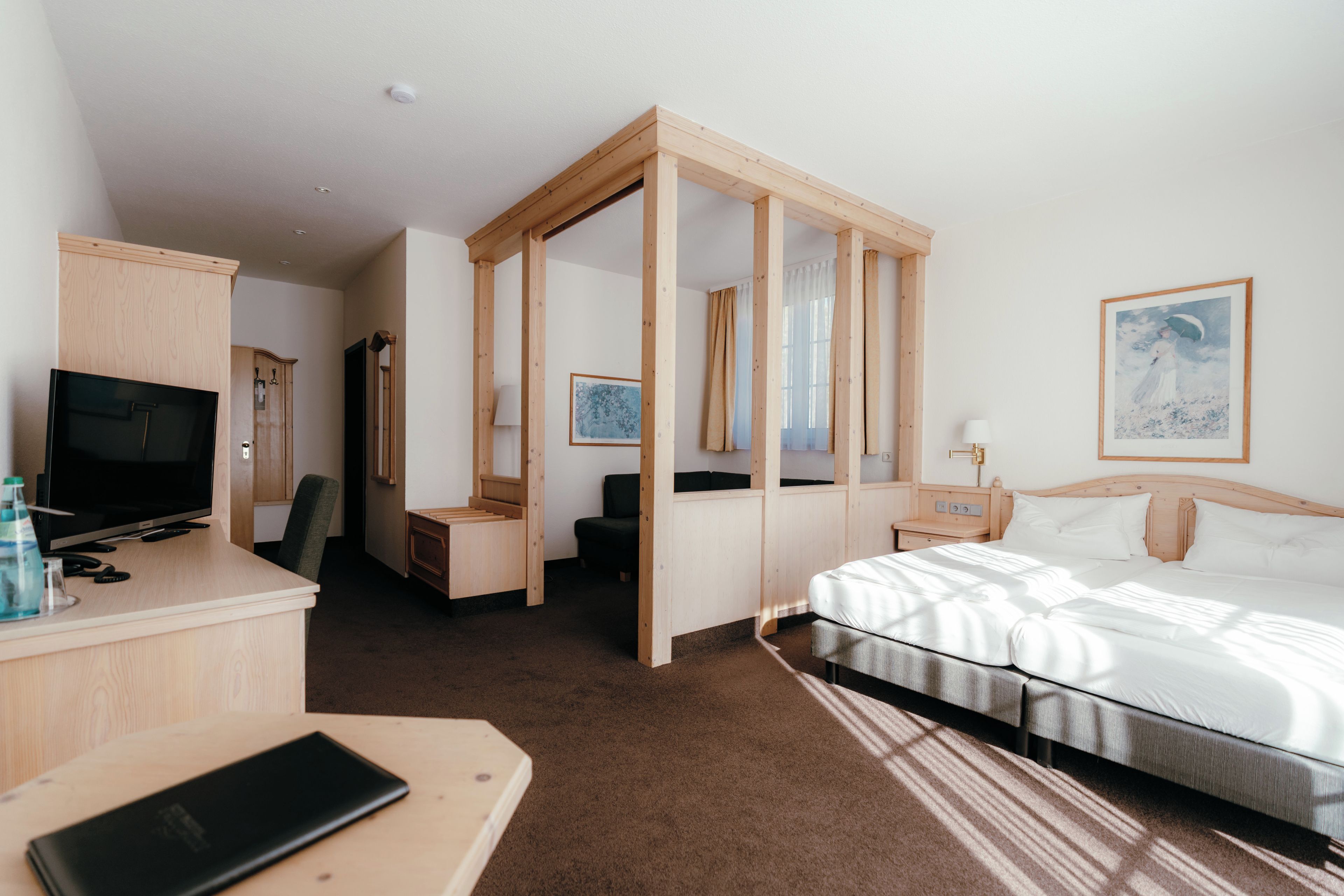 A hotel room with a bed, a desk with a TV, a wardrobe, and a bathroom.