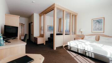 A hotel room with a bed, a desk with a TV, a wardrobe, and a bathroom.