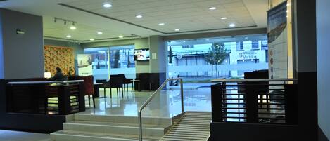 A lobby with a reception desk, seating area, and a staircase leading to an upper level.