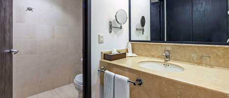A bathroom with a beige tiled floor, a sink with a mirror, a towel rack, and a toilet.