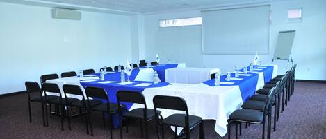 A conference room with multiple tables and chairs, arranged in rows.