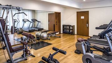Un gimnasio con máquinas de cardio, equipo de levantamiento de pesas y pelotas de ejercicio.