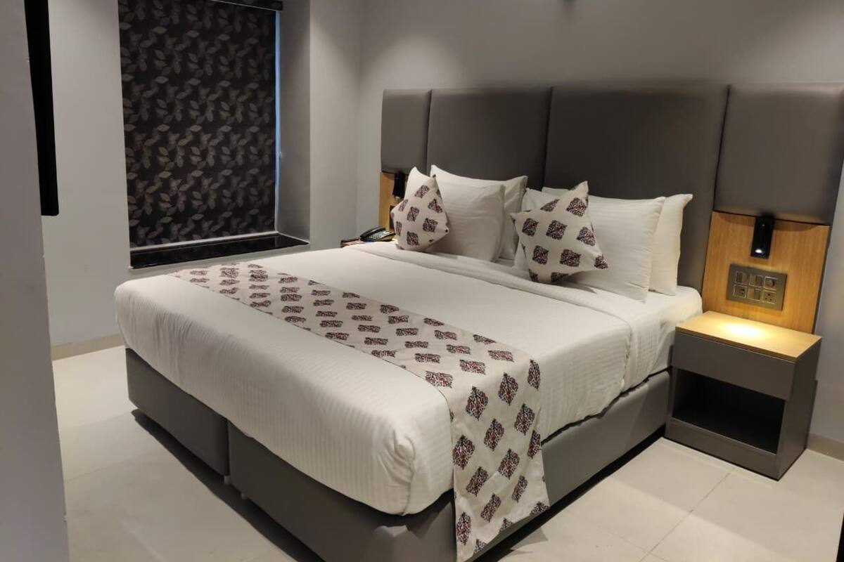 Un dormitorio moderno con una cama grande, mesitas de noche y una ventana con cortinas estampadas.