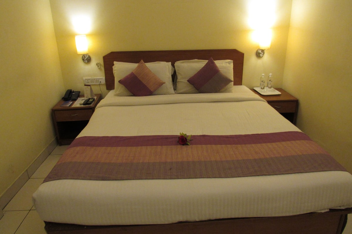 Una habitación de hotel con una cama grande, dos mesitas de noche y dos lámparas de pared.