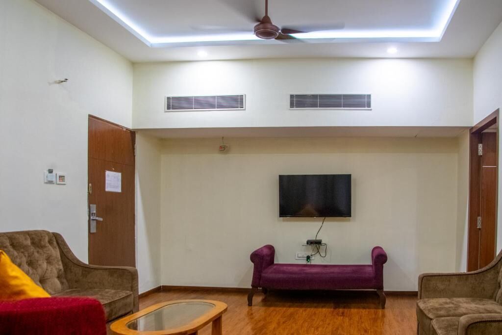 Una sala de estar con ventilador de techo, televisor montado y dos sofás.