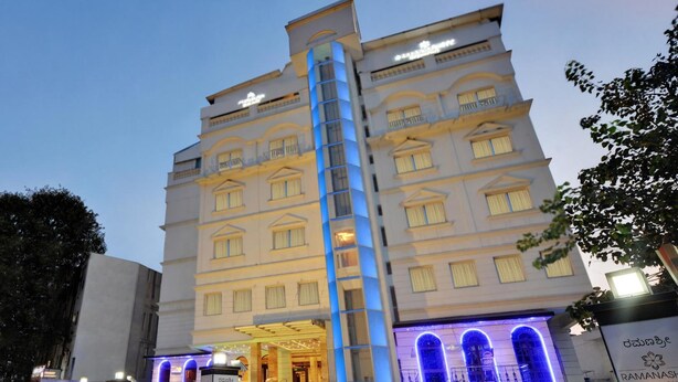 Un hôtel à plusieurs étages doté d’un escalier central, d’une entrée bien éclairée et d’une enseigne indiquant le nom « Ramanash ».