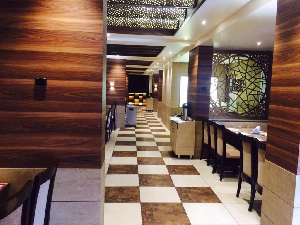 A hotel lobby with a checkered floor, wooden panel walls, and a reception desk.