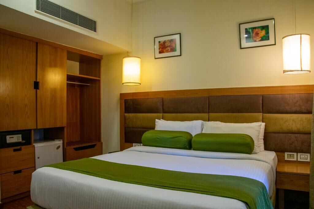 Quarto de hotel com uma cama, um guarda-roupa e uma mesa de cabeceira.