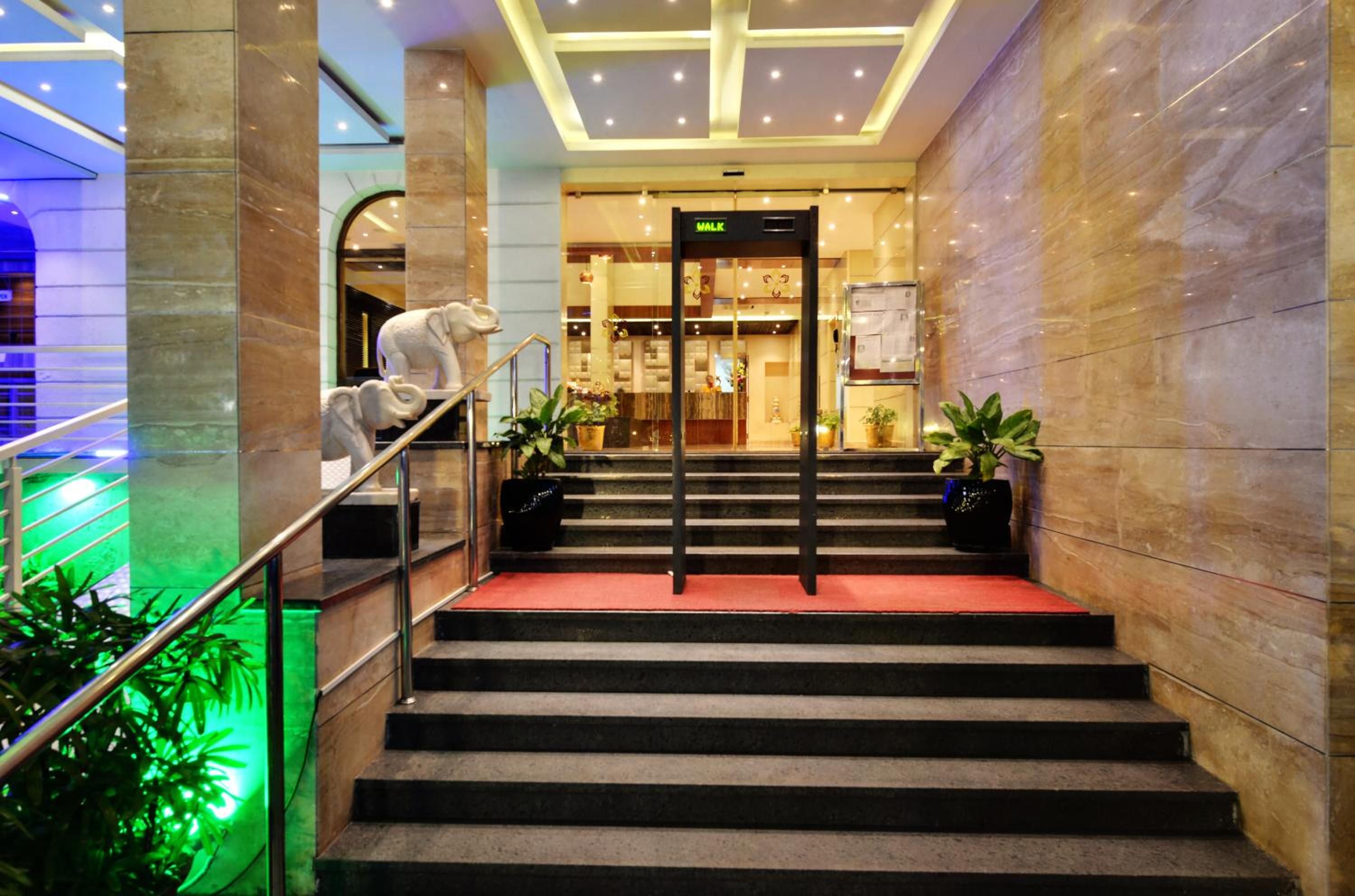 A hotel entrance with a marble staircase, a reception desk, and a sign indicating the direction to the lobby.