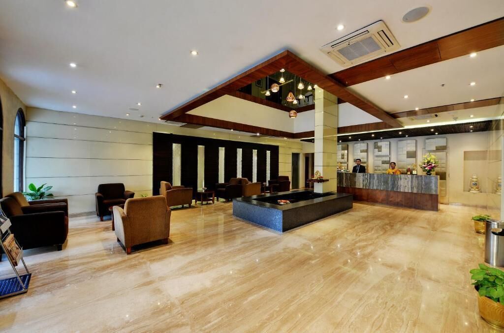 A hotel lobby with a reception desk, seating area, and a marble floor.