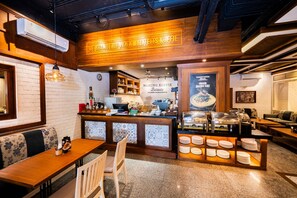 A café with a wooden counter, seating area, and a buffet with plates. - Stark Boutique Hotel and Spa Bali (Kuta)