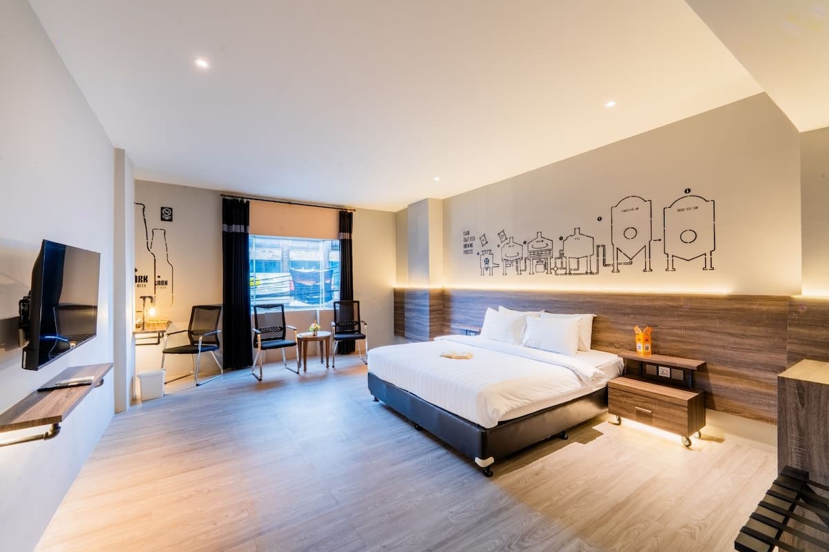 A modern hotel room with a large bed, a desk, and a TV.