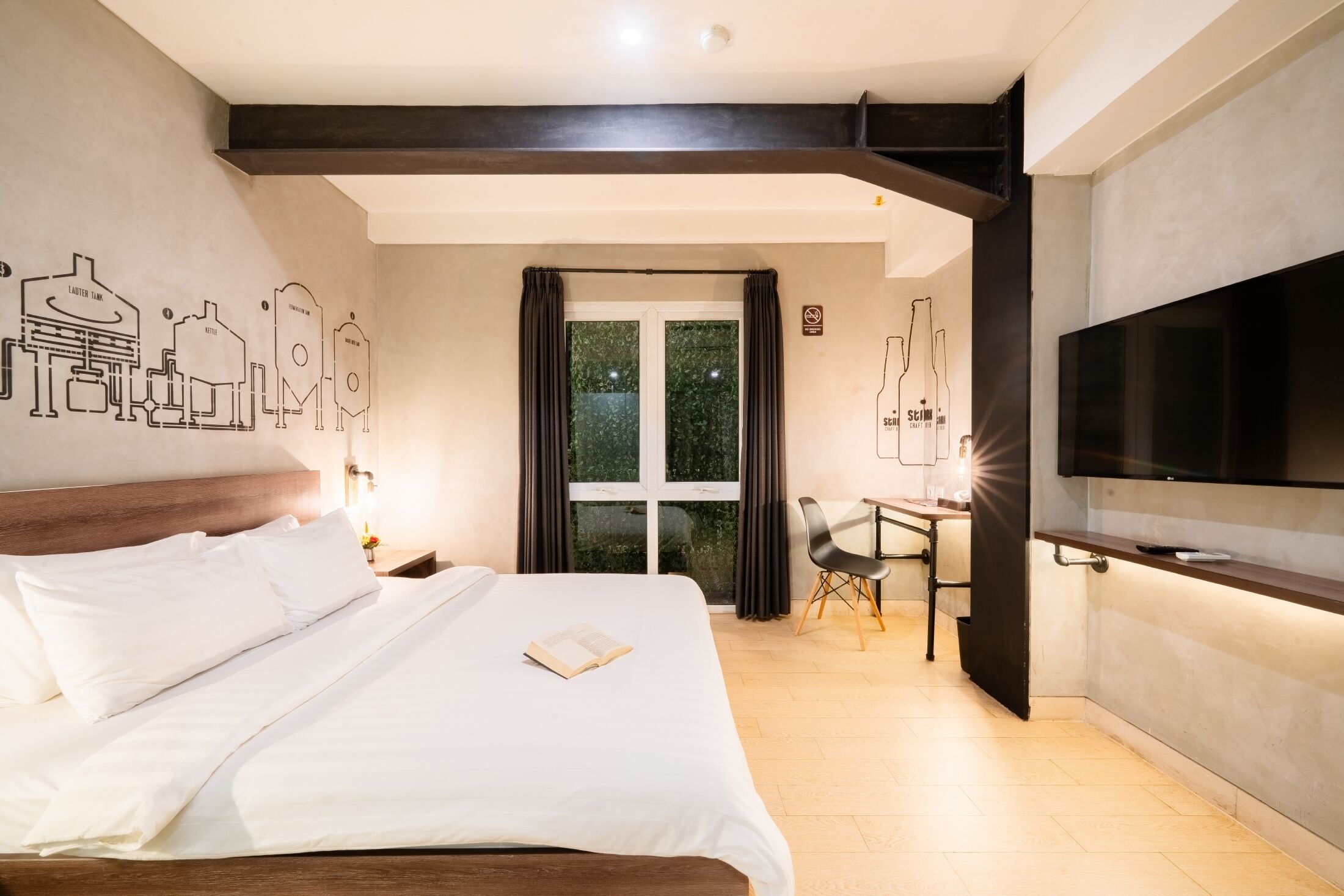 A hotel room with a large bed, a desk with a chair, a TV, and a window with curtains.