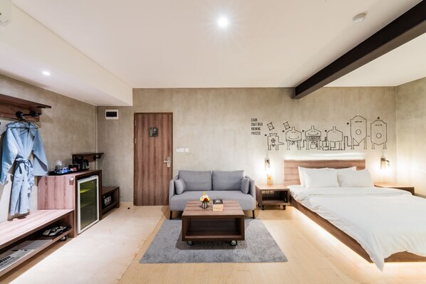 A modern bedroom with a grey sofa, a wooden coffee table, a bed, and a wall with a brewing station illustration. - Stark Boutique Hotel and Spa Bali (Kuta)
