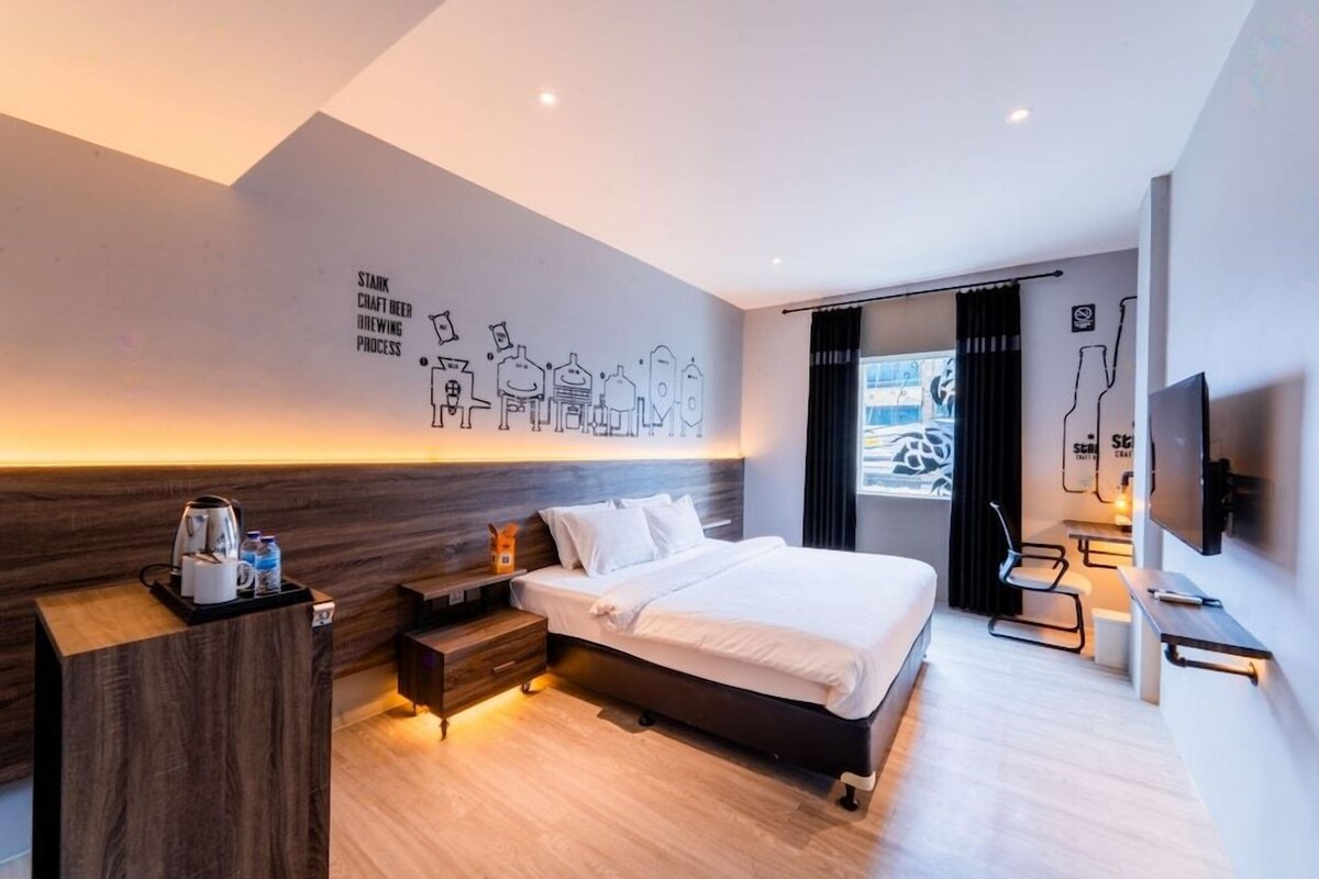 A modern hotel room with a bed, bedside table, and a wall-mounted TV.