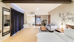 Une chambre d’hôtel moderne dotée d’un grand lit, d’un canapé, d’une table basse et d’un coin salon avec vue sur la cuisine.