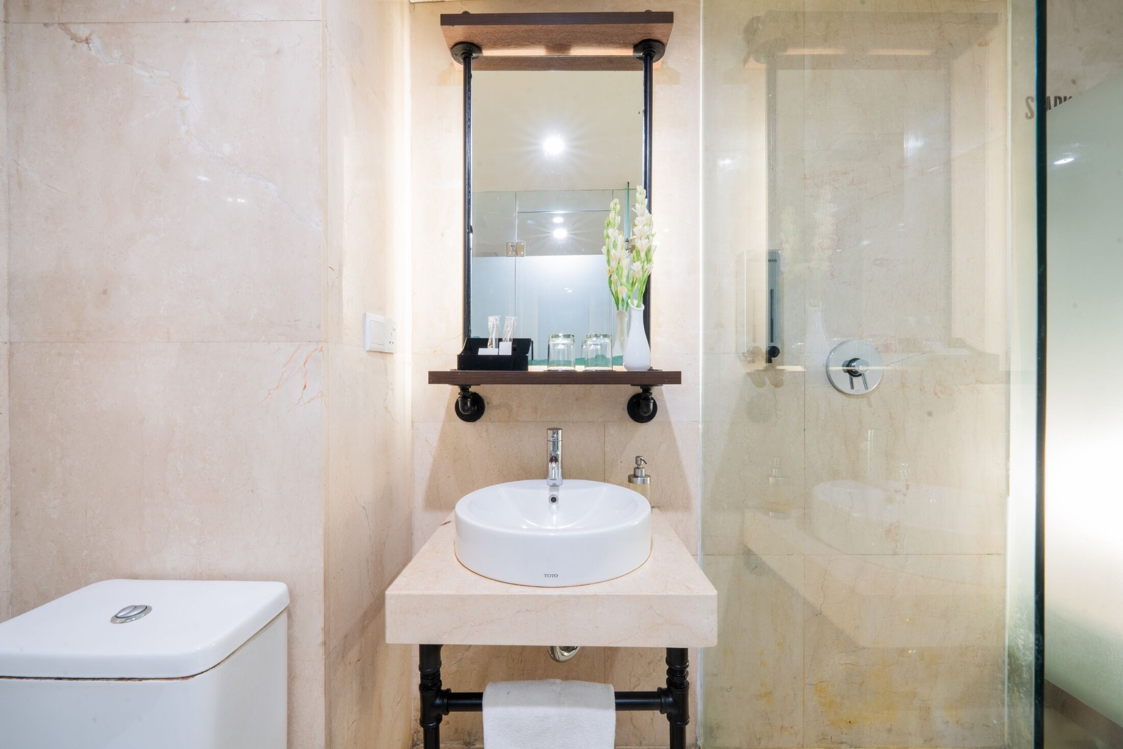 Un baño con lavamanos blanco, un espejo y una cabina de ducha de vidrio.