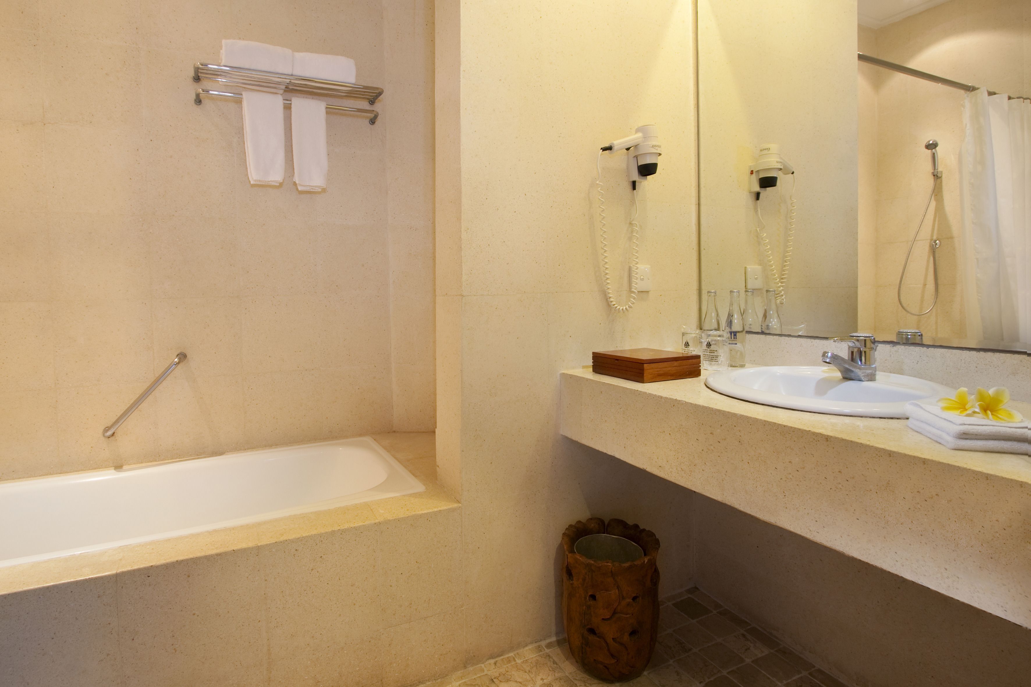 A bathroom with a bathtub, a sink, a mirror, and a hairdryer.