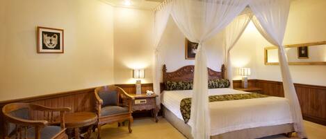 A bedroom with a four-poster bed, wooden furniture, and a checkered rug.