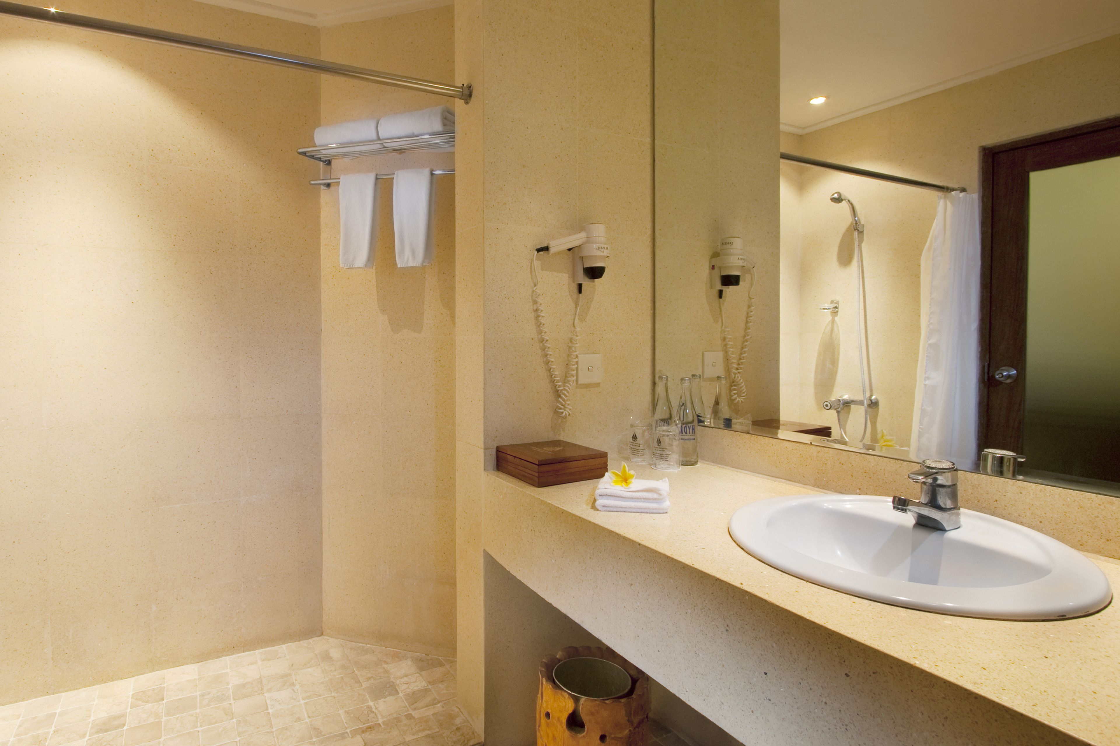 A bathroom with a sink, mirror, towel rack, and shower area.