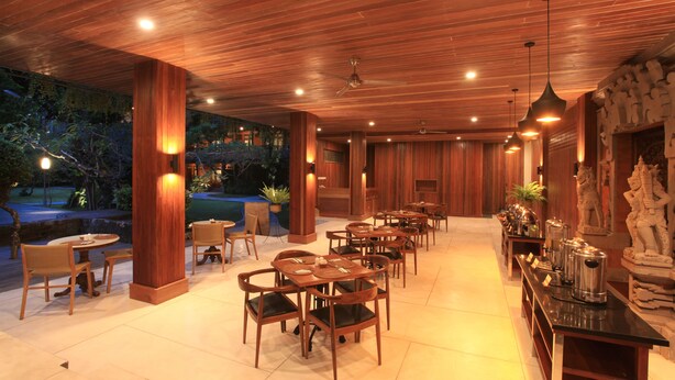 A restaurant with wooden tables and chairs, a bar area, and a view of the outdoors. - Matahari Bungalow (Kuta)