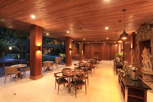 Un restaurante con mesas y sillas de madera, una zona de bar y vistas al exterior.