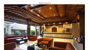 A reception area with a wooden ceiling, red sofas, and a reception desk. - Matahari Bungalow (Kuta)